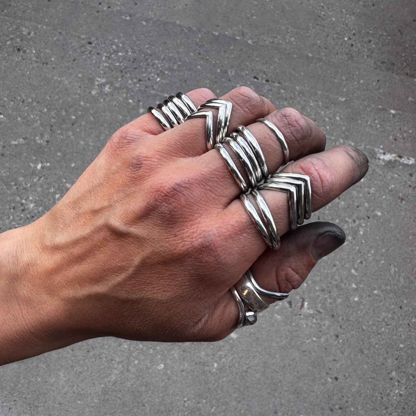 Hand wearing multiple silver stacker rings with chevron zigzag patterns
