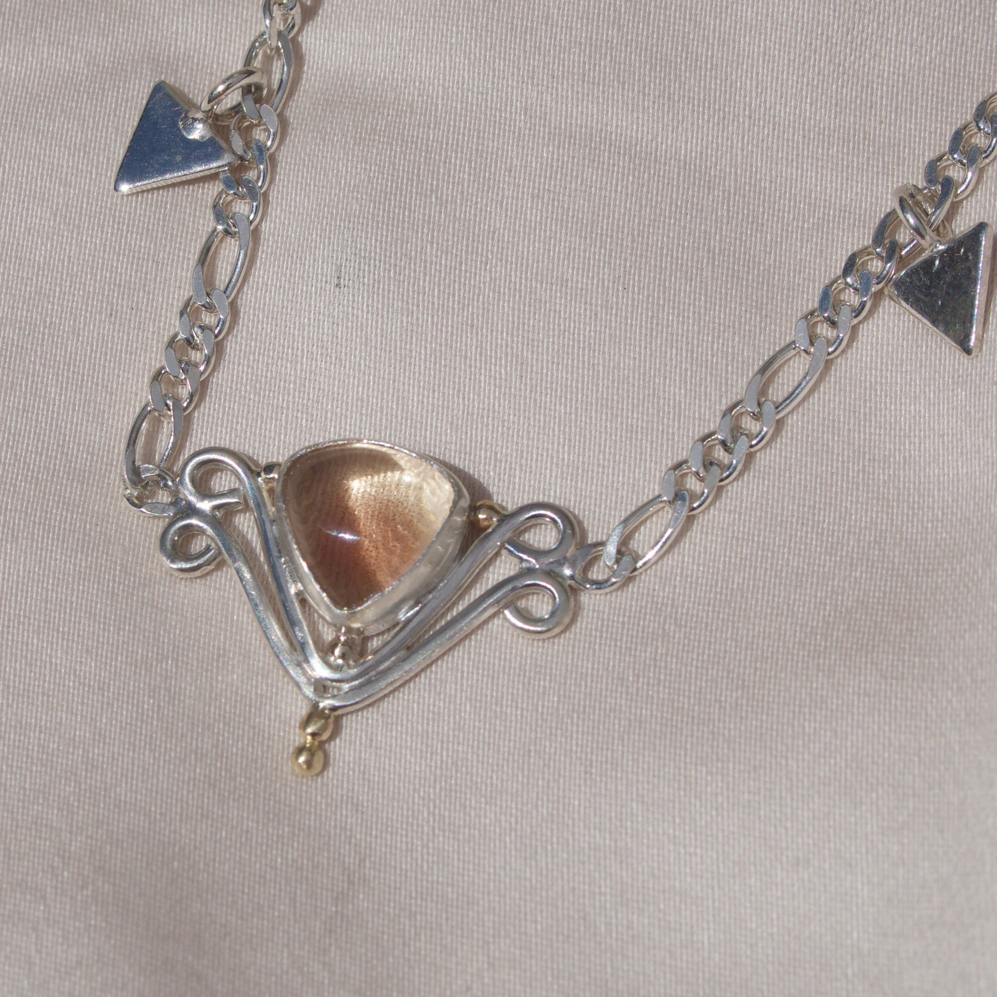 Silver necklace with a pendant on a light gray background