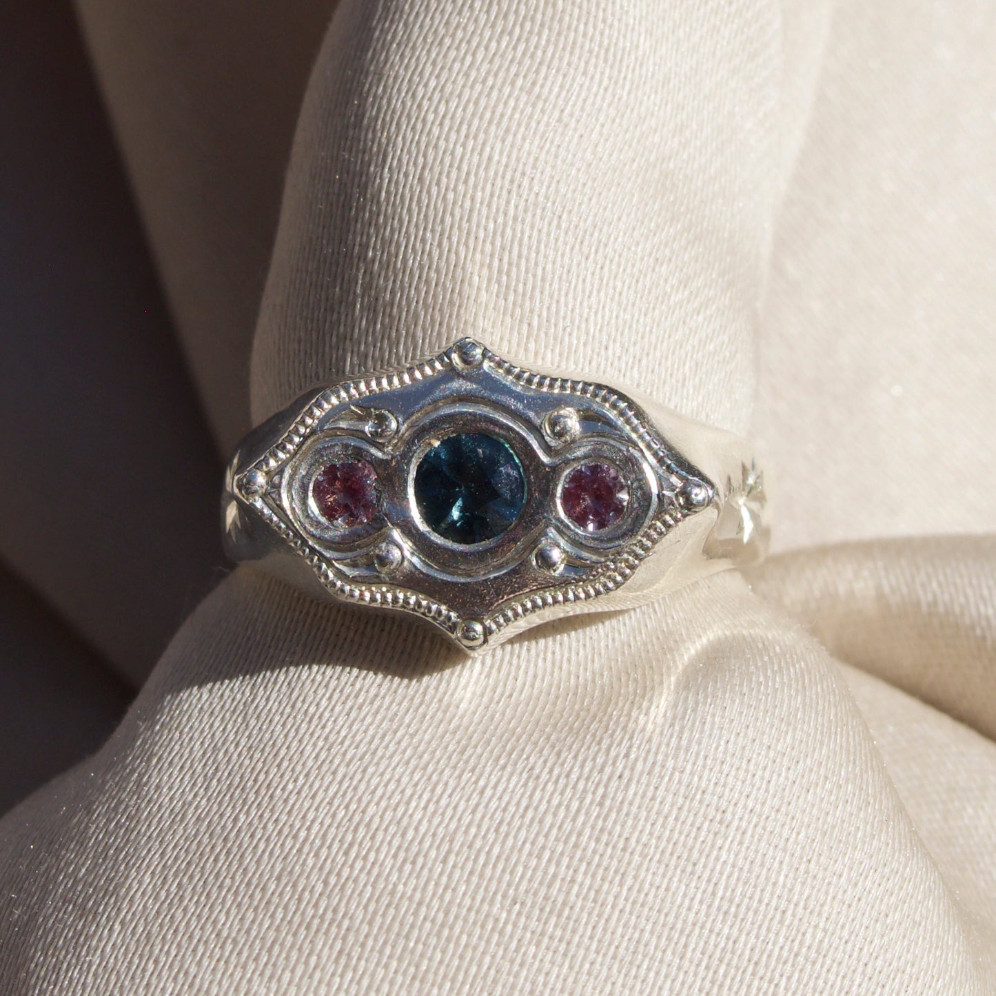Silver ring with gemstones on a beige fabric background