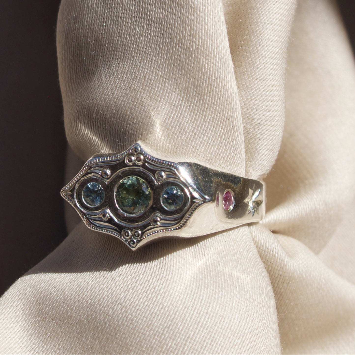 Silver ring with gemstones on a white fabric background