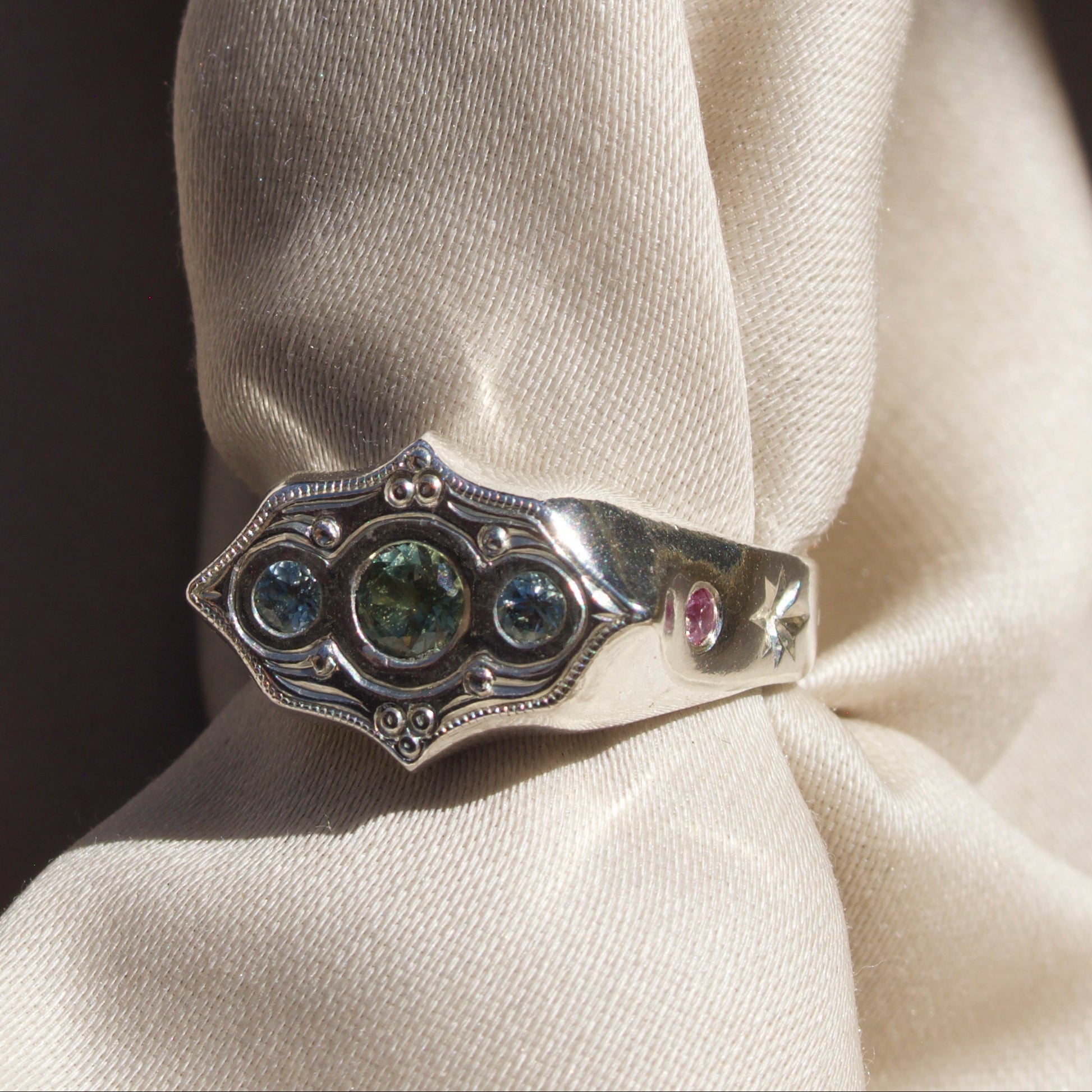 Silver ring with gemstones on a white fabric background